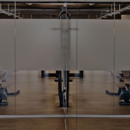 Impressionen aus unserem Studio | Fitnessraum mit Geräten hinter einer Glasscheibe