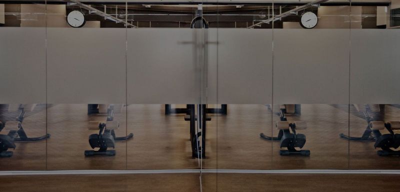 Impressionen aus unserem Studio | Fitnessraum mit Geräten hinter einer Glasscheibe